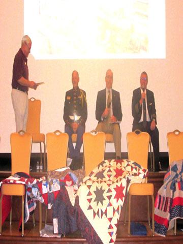 panelists on stage with quilts in front.jpg